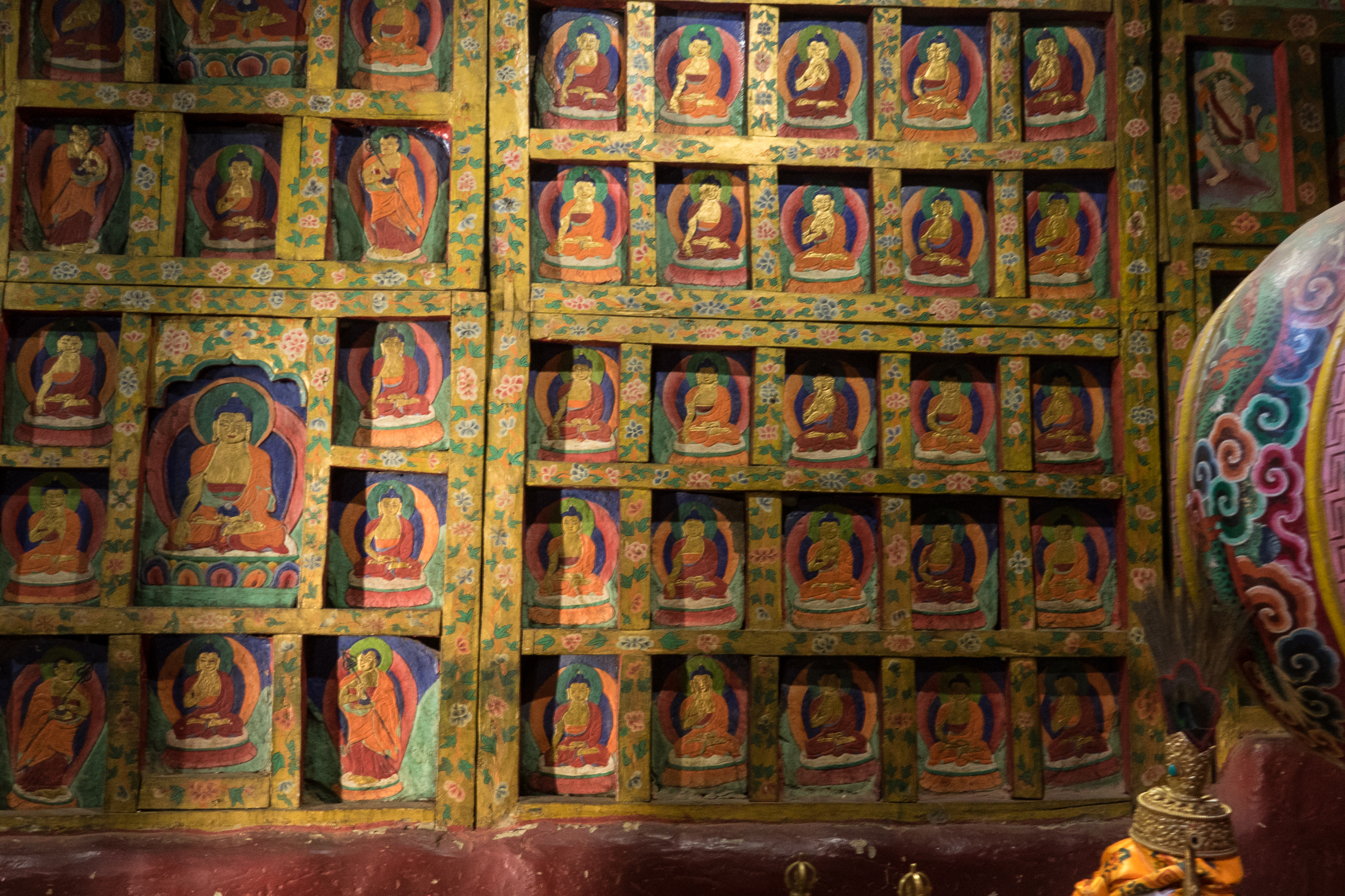 L'intérieur de Ghar Gompa : Murs tapissés de cloisons en bois et pierres peintes représentant Bouddah